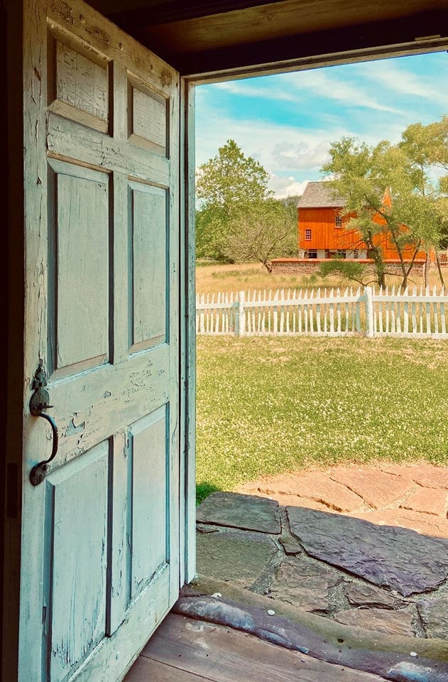 A door to an outside area with a fence and trees.